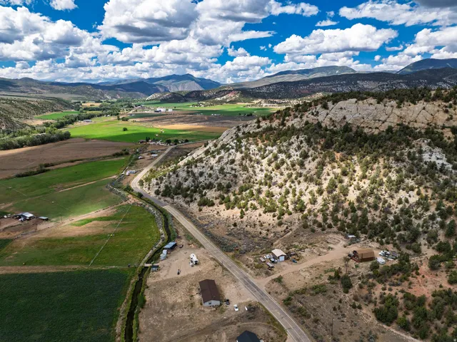 Expansive land parcel featuring a winding road, natural rock formations, and distant mountains