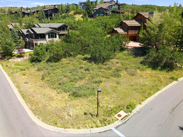 Corner lot featuring sloped terrain and surrounding mature trees