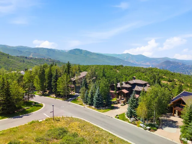 Mountain backdrop with a multi-level residence featuring a prominent stone and wood exterior