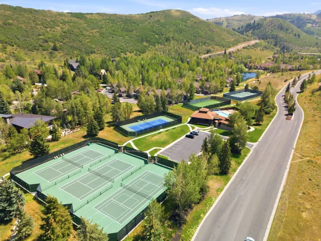 Multiple tennis courts, a swimming pool, and a clubhouse surrounded by mature trees