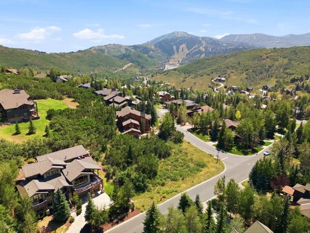 Expansive property featuring a large residence with multiple balconies, a paved driveway, and mature landscaping, surrounded by a mountainous backdrop