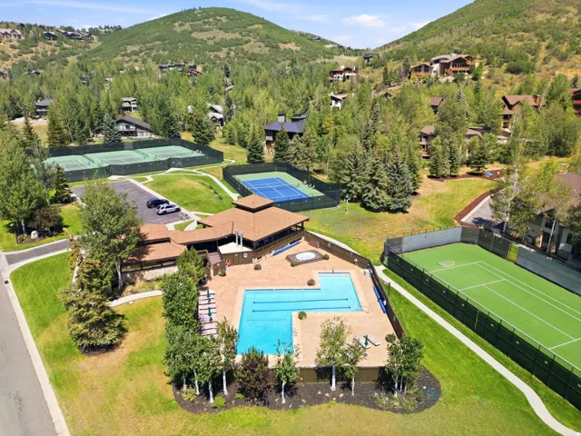 Expansive outdoor pool with a surrounding patio, multiple tennis courts, and a spa