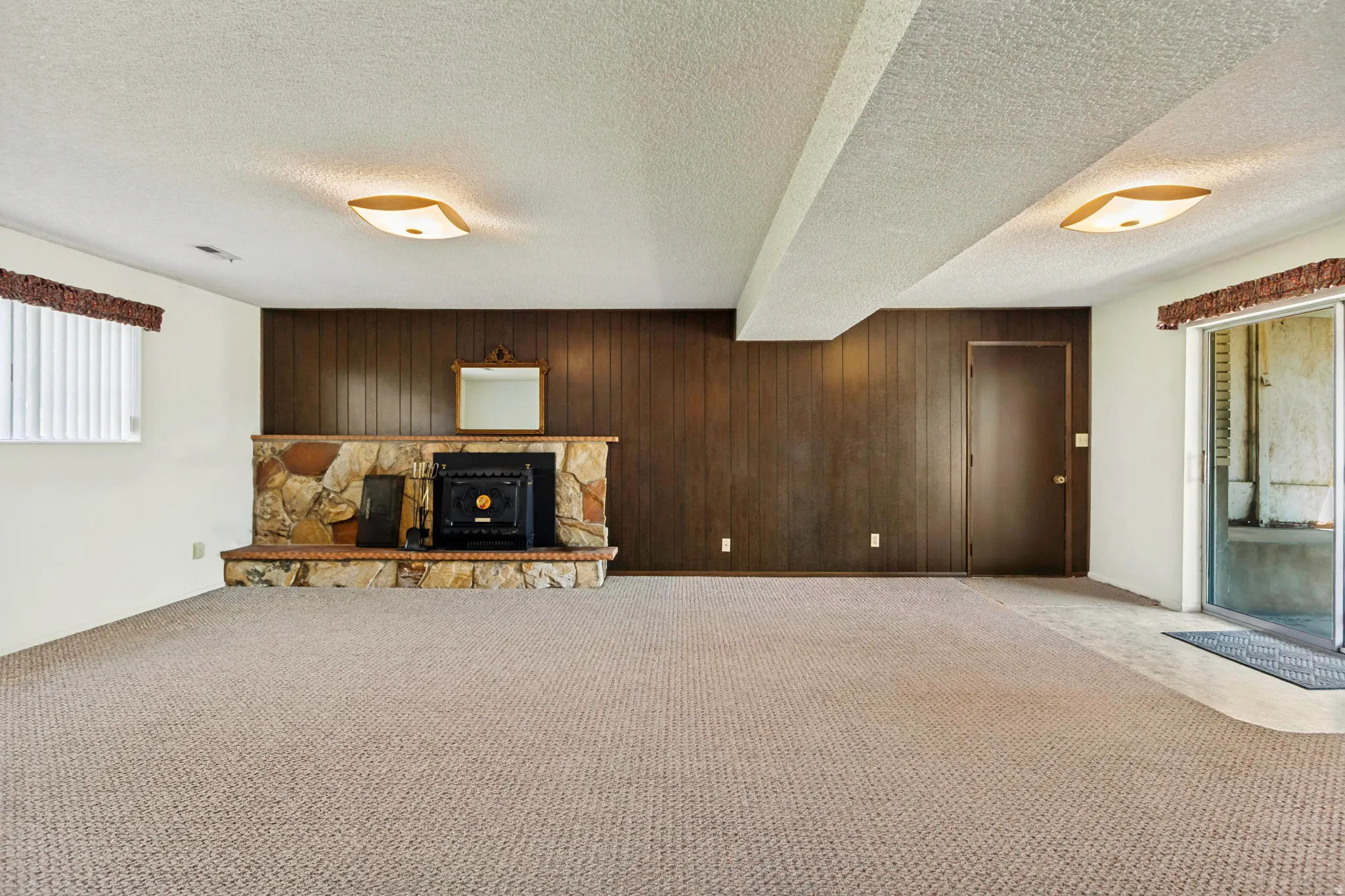 Spacious living room in basement with wood burning fireplace.