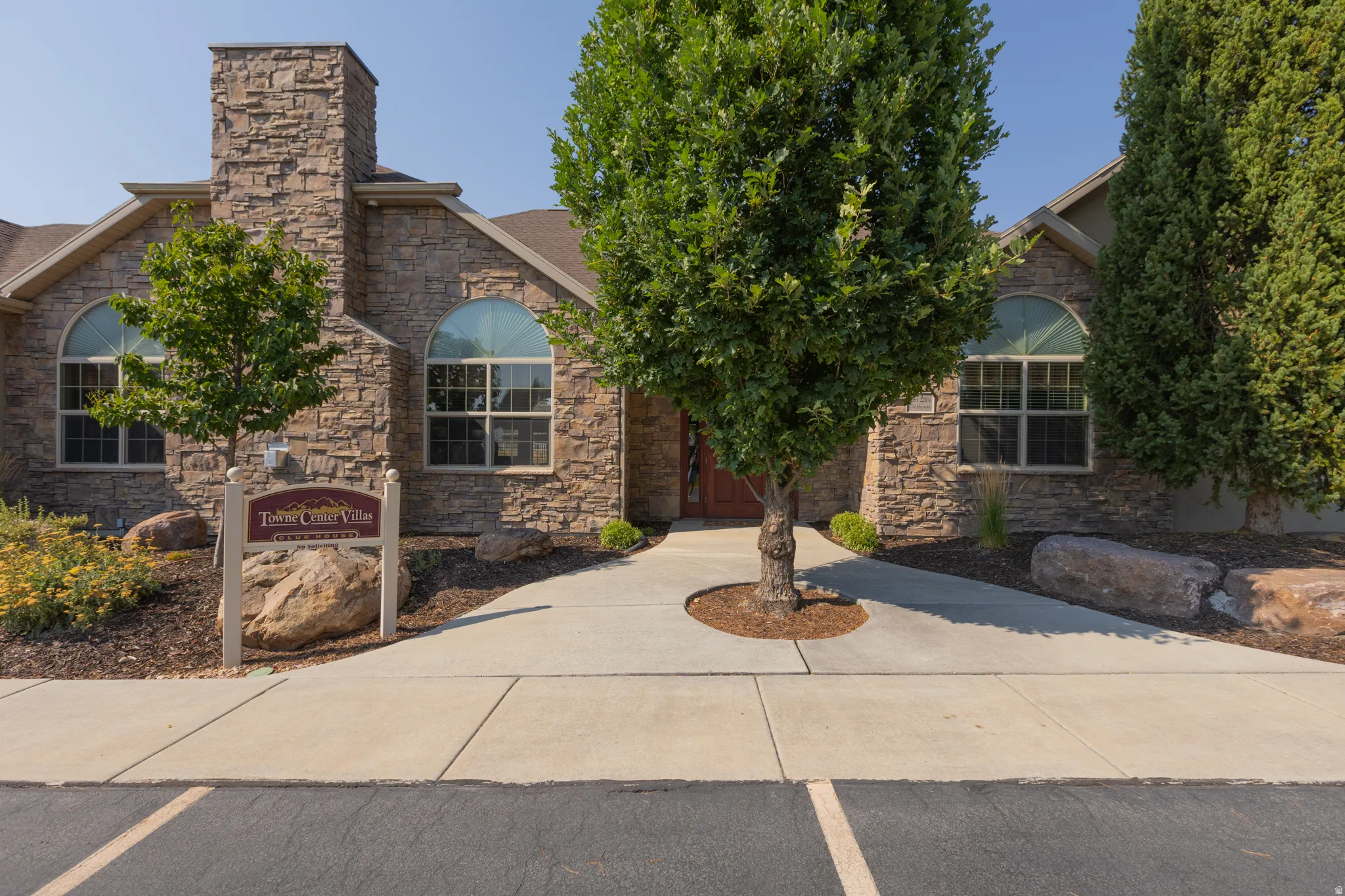 Stone facade with arched windows, prominent stone chimney, and a welcoming entryway with a red door