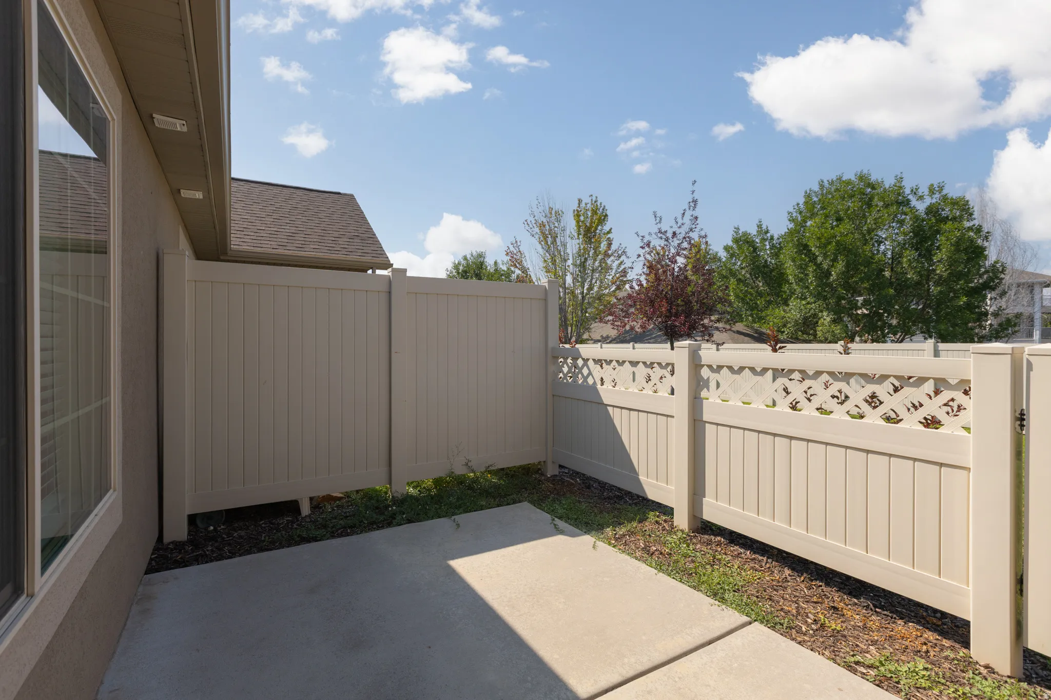 Private patio area with concrete surfacing, enclosed by a perimeter fence with lattice detailing