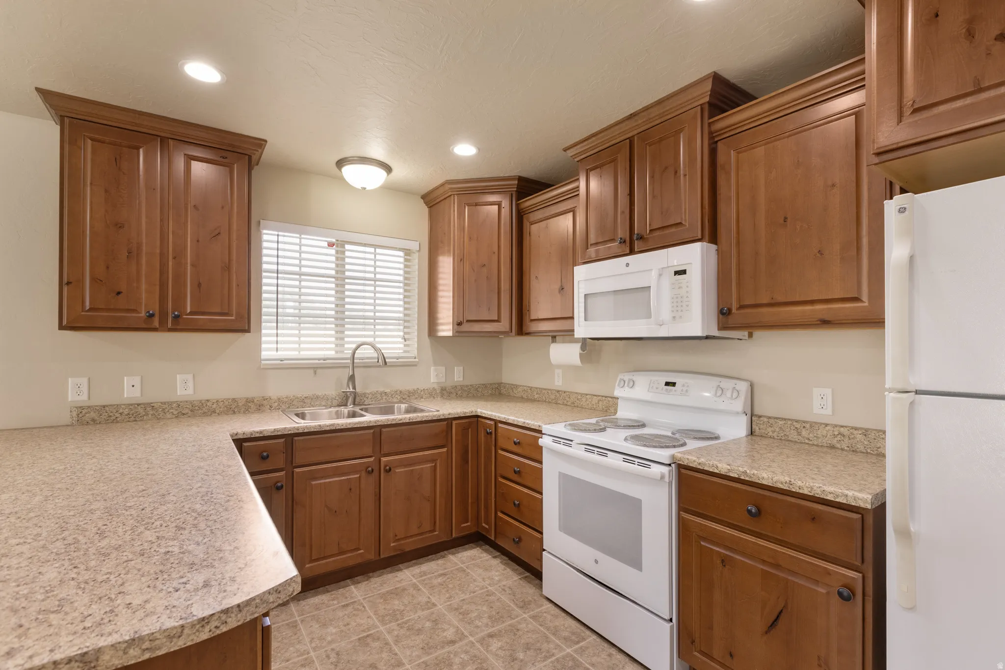 Kitchen featuring wood-finish cabinetry, light-toned countertops, and a double basin sink with a gooseneck faucet