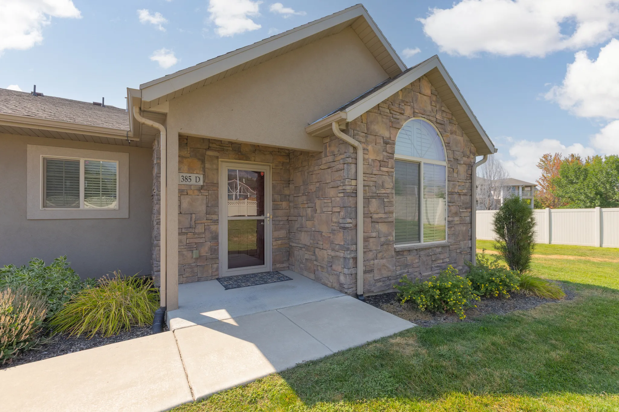 Stone veneer exterior with an arched window, covered entry, and concrete walkway