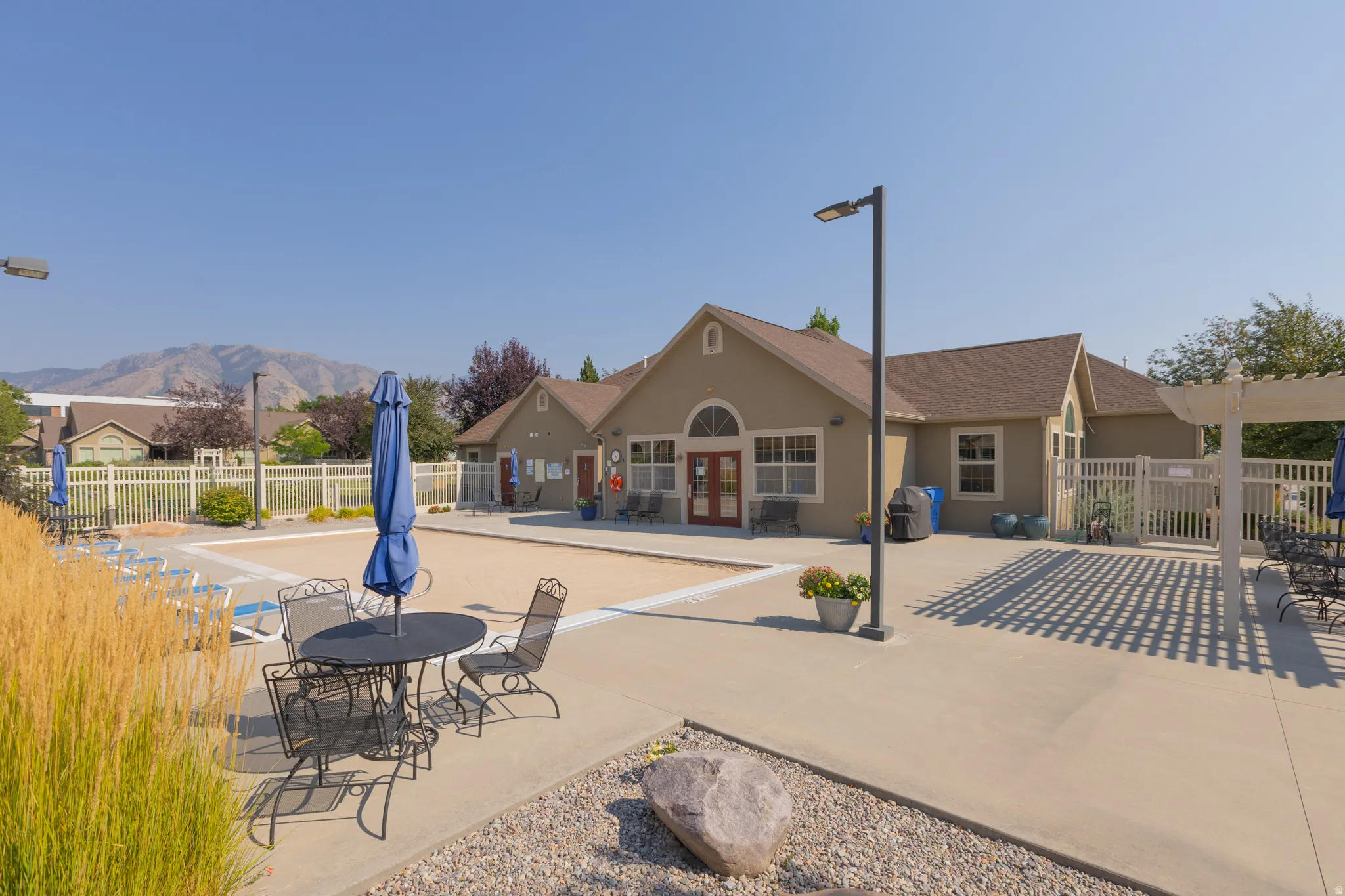 Outdoor patio area featuring concrete hardscaping, a white pergola, and a fenced-in recreation space