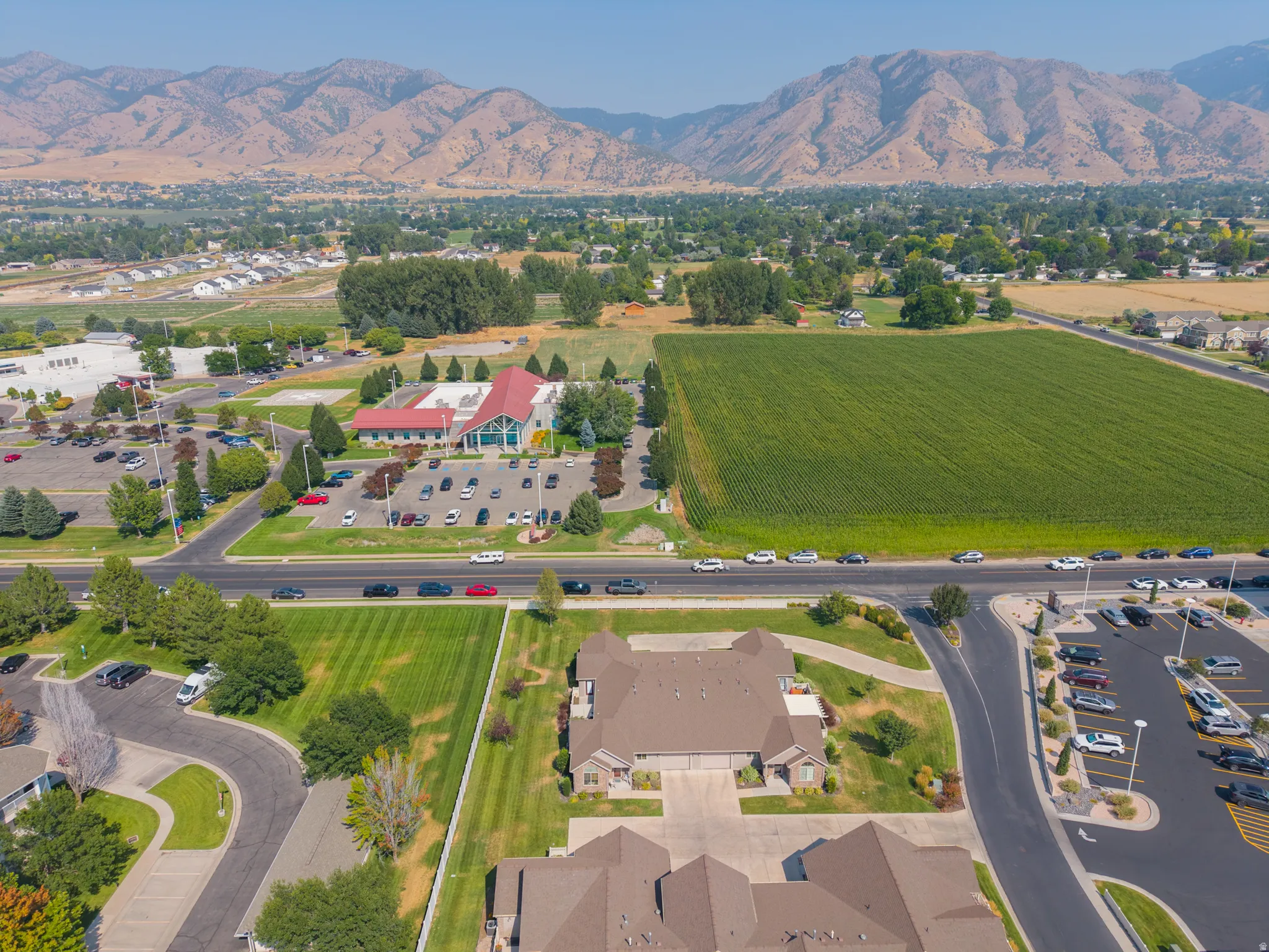 Expansive property featuring a paved parking lot, manicured green spaces, and a mountainous backdrop