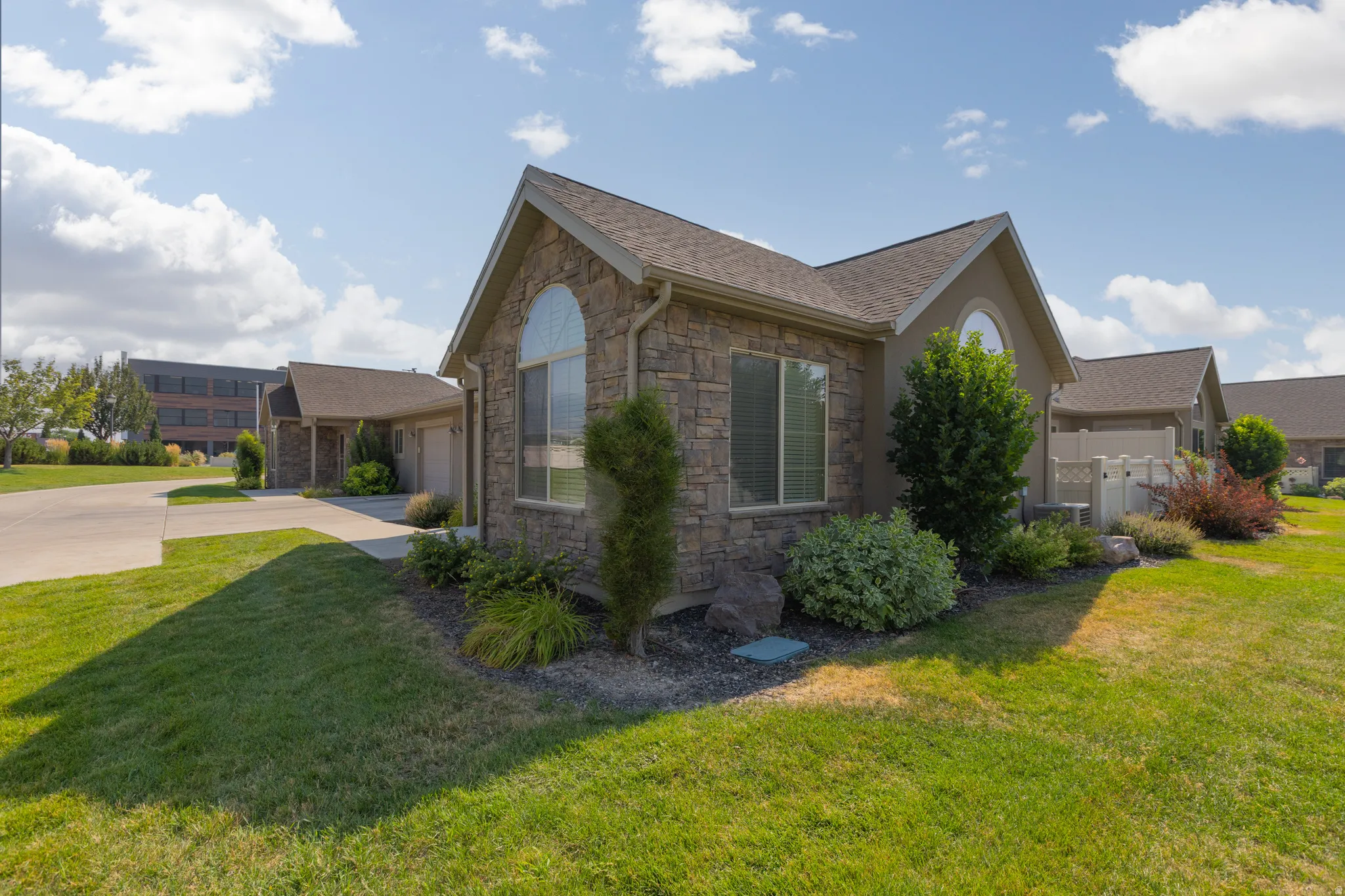 Stone veneer exterior with an arched window and landscaped planting beds