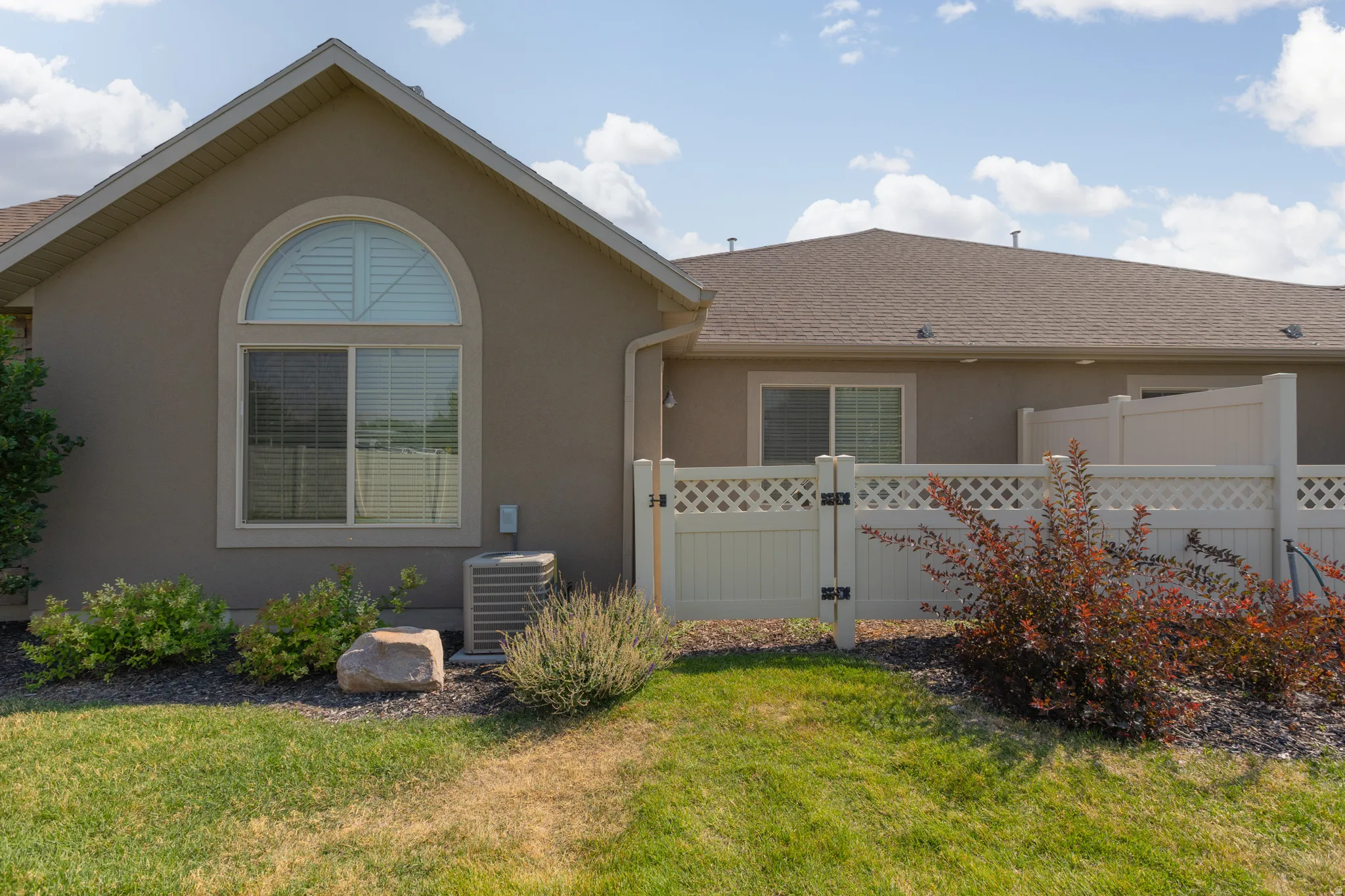 Exterior featuring a stucco finish, arched window with shutters, and a sloped roofline