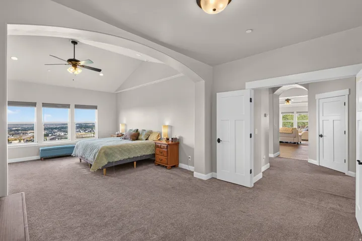 Vaulted ceiling with archway, recessed lighting, ceiling fan, carpet flooring, and multiple white-framed windows