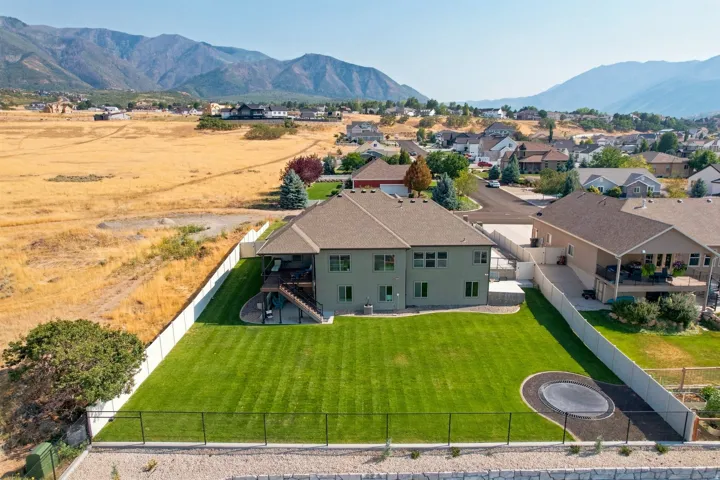 Expansive green lawn with a white privacy fence, featuring a multi-level deck and a mountain backdrop