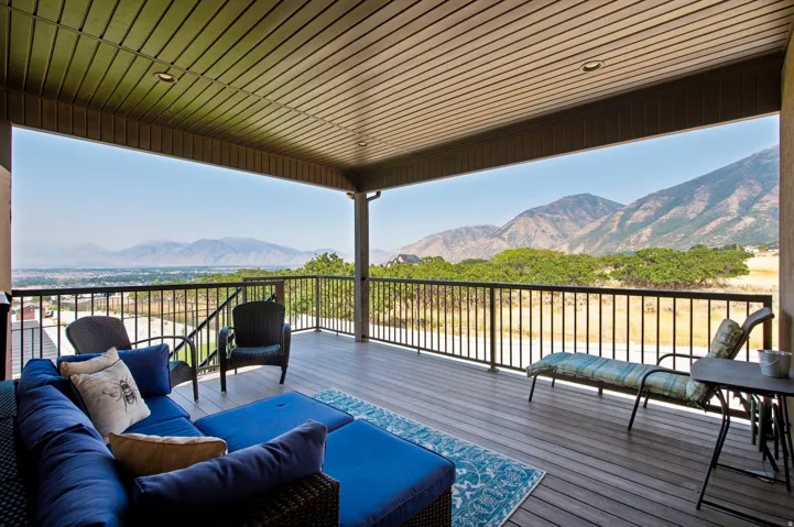 Covered deck with composite decking, black metal railings, recessed lighting, and a prominent mountain backdrop
