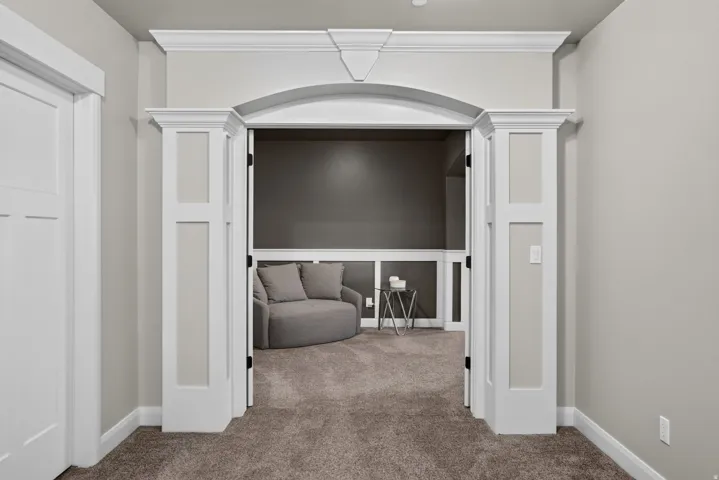 Archway entry with decorative molding, paneled walls, and carpet flooring