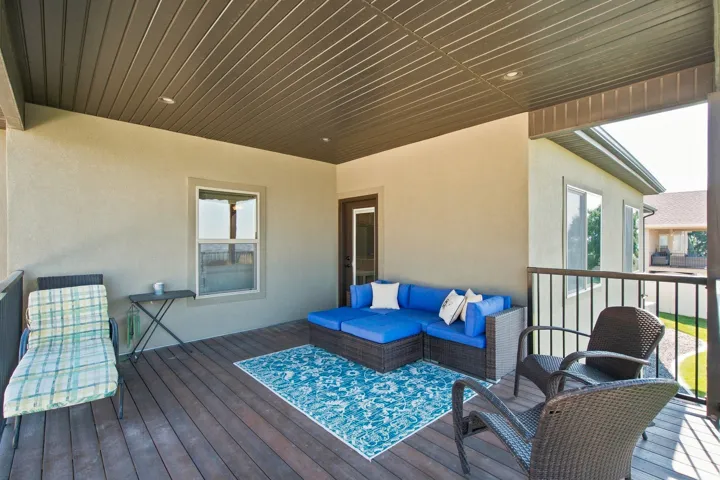 Covered balcony with wood-finish flooring, recessed lighting, and a dark metal railing
