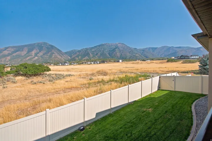 Manicured lawn with a gravel border, enclosed by a privacy fence, with distant mountains