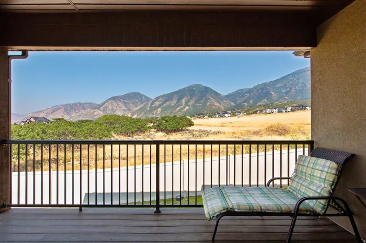 Covered outdoor patio with wood-finish flooring and a black metal railing