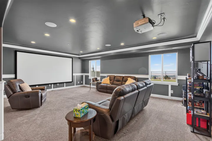 Dedicated entertainment room featuring a large projection screen, recessed lighting, and a ceiling-mounted projector