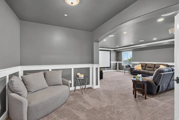 Expansive room featuring recessed lighting, a projection screen, built-in archway, and wainscoting with decorative trim