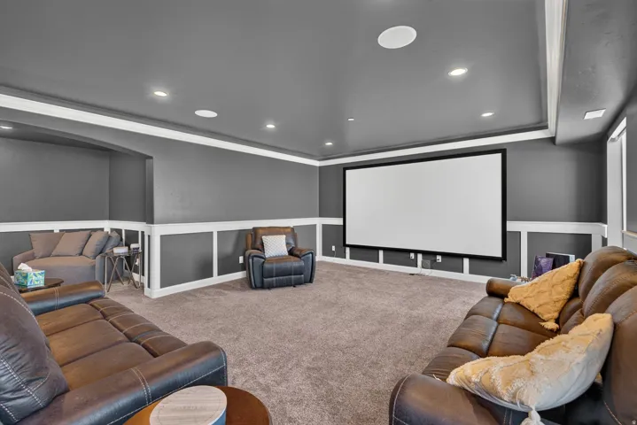 Integrated projection screen, recessed ceiling lighting, wall paneling, built-in ceiling speakers, and carpet flooring