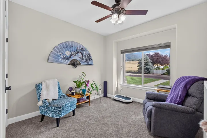 Recessed window featuring a mountain backdrop, ceiling fan with integrated lighting, light gray carpet flooring, and neutral wall paint
