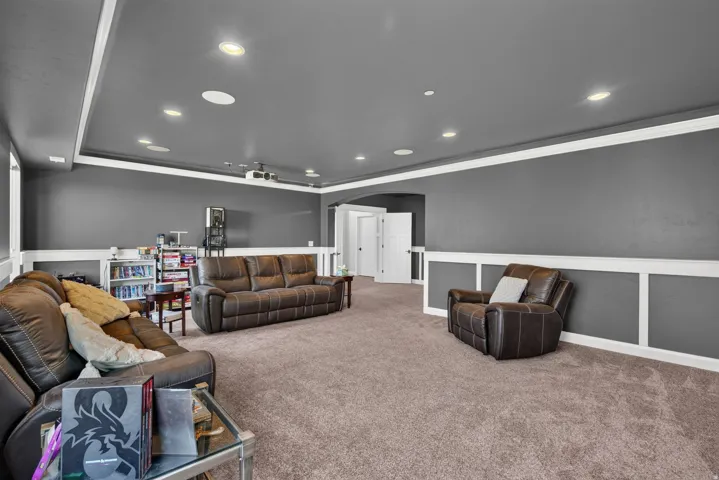 Spacious room featuring neutral carpeting, recessed lighting, and a chair rail with decorative wainscoting