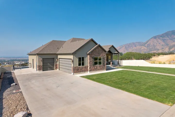 Stucco exterior with stone accents, covered porch, attached two-car garage, and concrete driveway