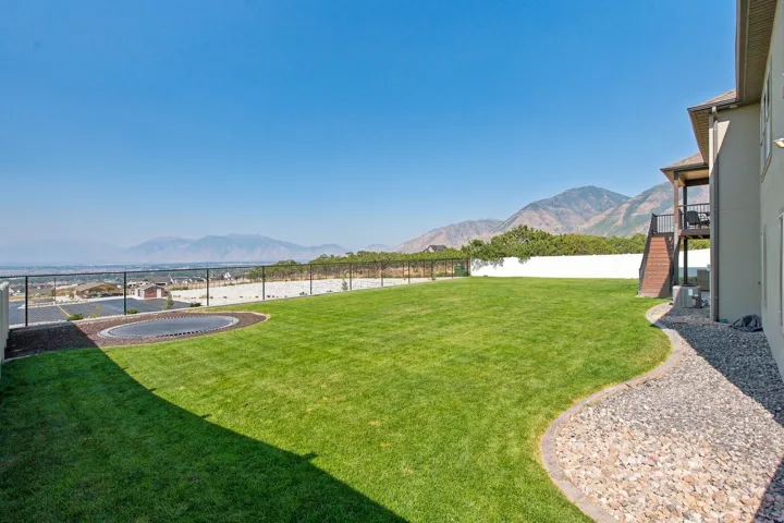Expansive grassy lawn with a gravel pathway and elevated deck