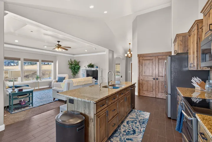 Kitchen featuring wood cabinetry, granite countertops, an island with an undermount sink, and wood-finish flooring