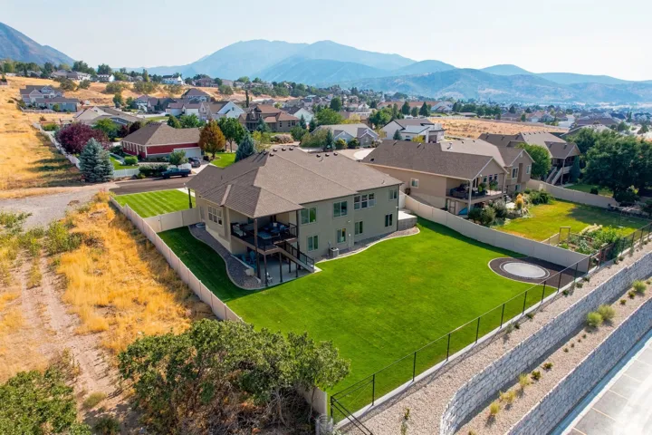 Expansive green lawn, multi-level deck, fenced backyard, and surrounding mountain scenery