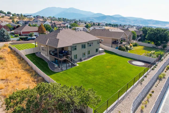 Expansive backyard with manicured lawn, multi-level deck, covered patio, and a privacy fence