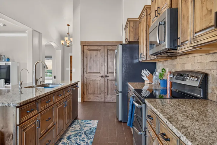 Granite countertops, stainless steel appliances, wood-finish cabinetry, tile flooring, and arched doorways