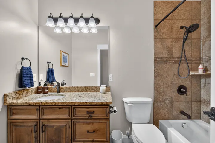 Vanity with granite countertop, integrated sink, and wood-finish cabinetry