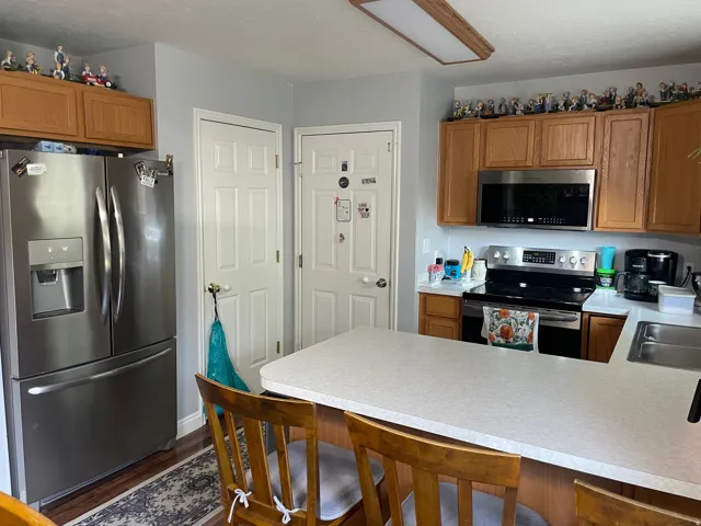 Kitchen featuring wood-finish cabinetry, stainless steel appliances, and a light-colored countertop