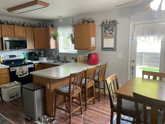 Kitchen featuring wood-finish flooring, light wood cabinetry, stainless steel appliances, and a breakfast bar with seating
