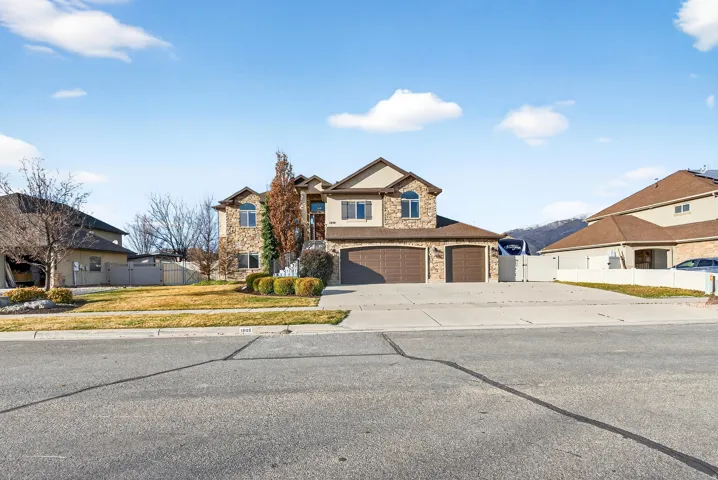 Two-story residence featuring stone and stucco exterior, arched windows, and an attached three-car garage