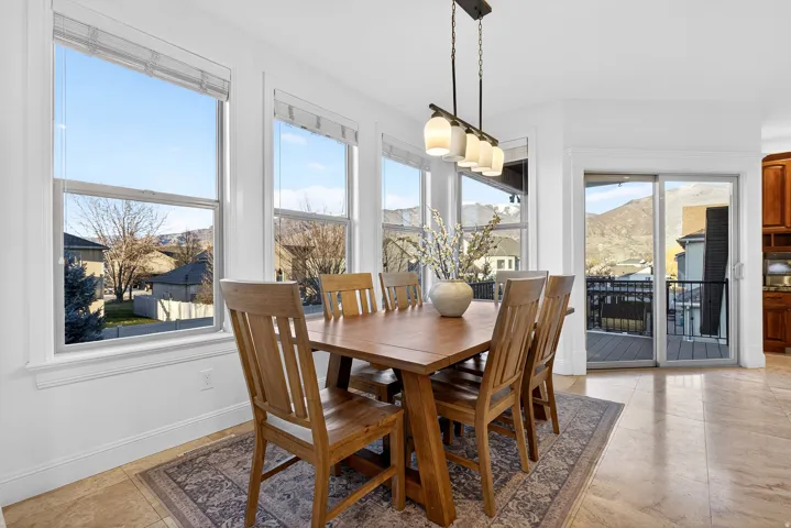 Dining space featuring multiple large windows, a sliding glass door, an outdoor deck, and light-toned tile flooring