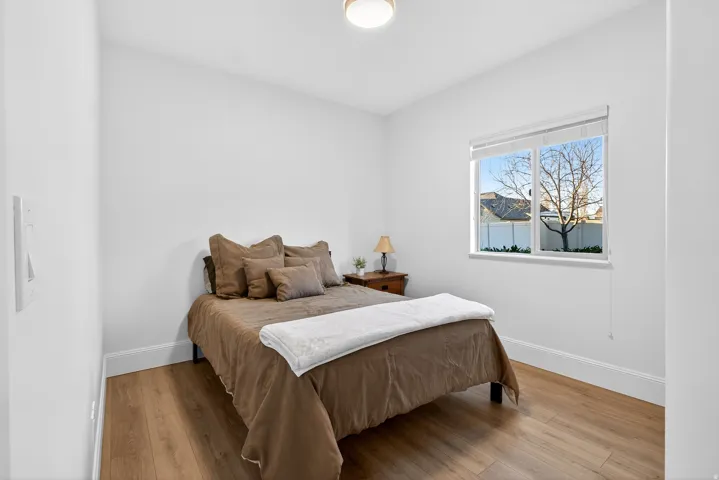 White walls with a single window, wood-finish flooring, and a flush-mount ceiling light fixture