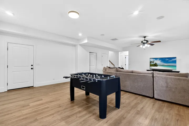 Spacious room featuring wood-finish flooring, recessed lighting, and a ceiling fan
