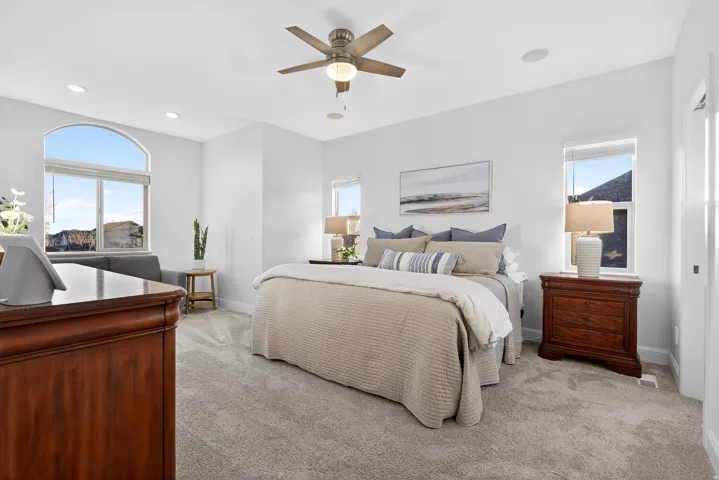 Carpeted bedroom featuring recessed lighting, a ceiling fan, and multiple windows including an arched transom
