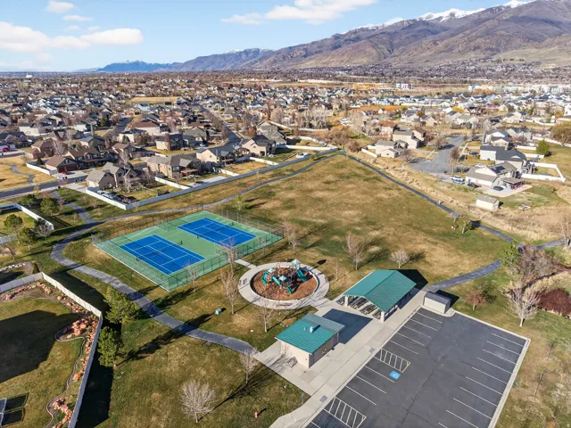 Community amenities featuring two tennis courts, a playground, a covered pavilion, and a paved parking area