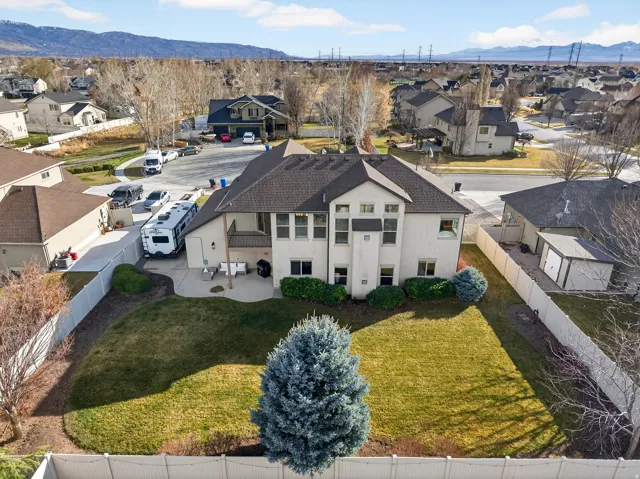 Expansive rear yard with green lawn, mature trees, and a white privacy fence