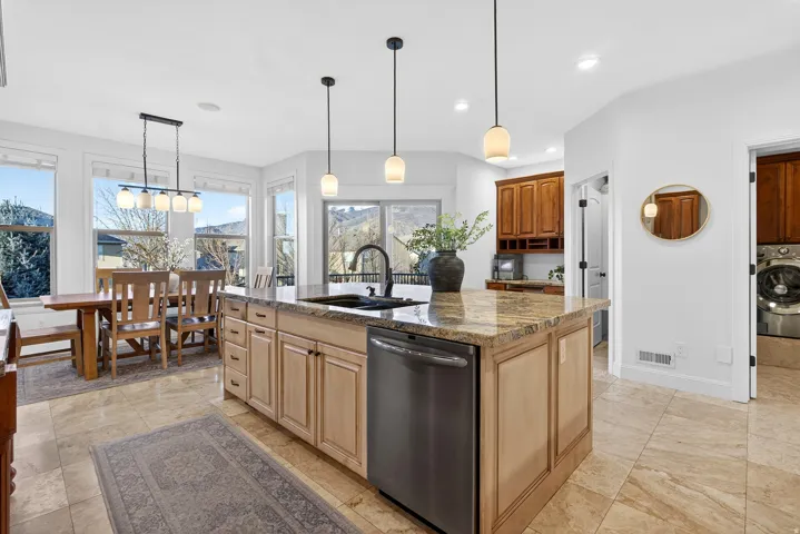 Central kitchen island with a stone-finish countertop and undermount sink