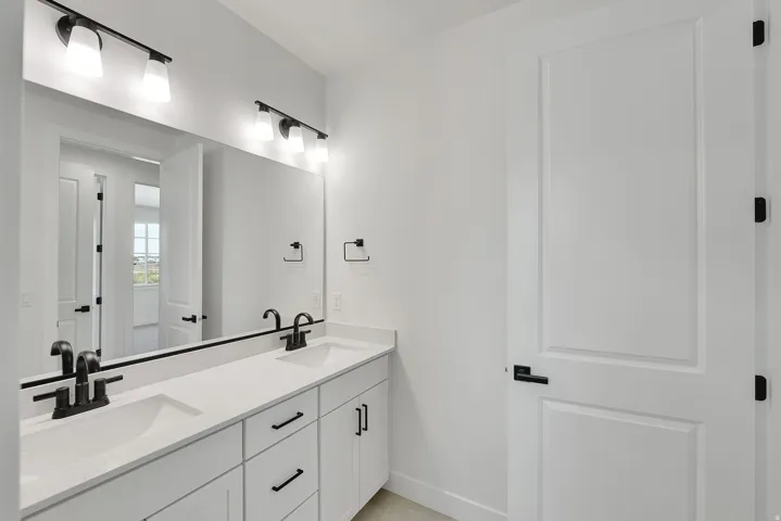 Dual vanity with undermount sinks, white cabinetry, quartz-finish countertop, and matte black fixtures