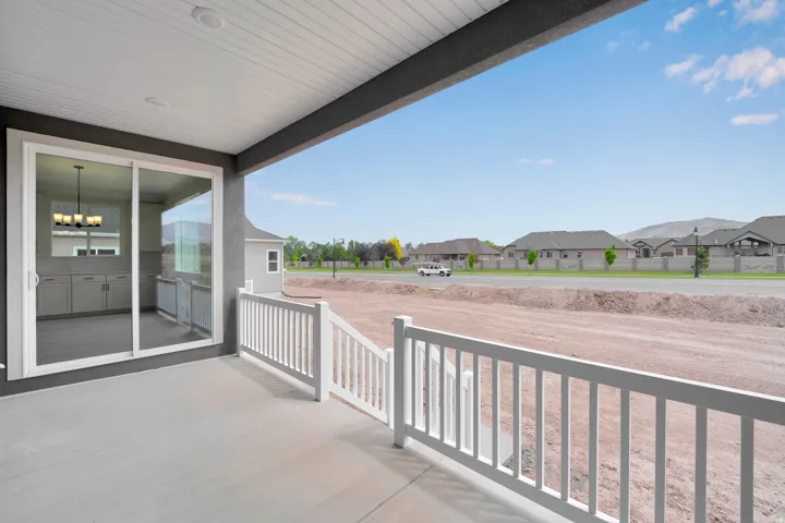 Covered patio with a concrete surface, white railing, and sliding glass door