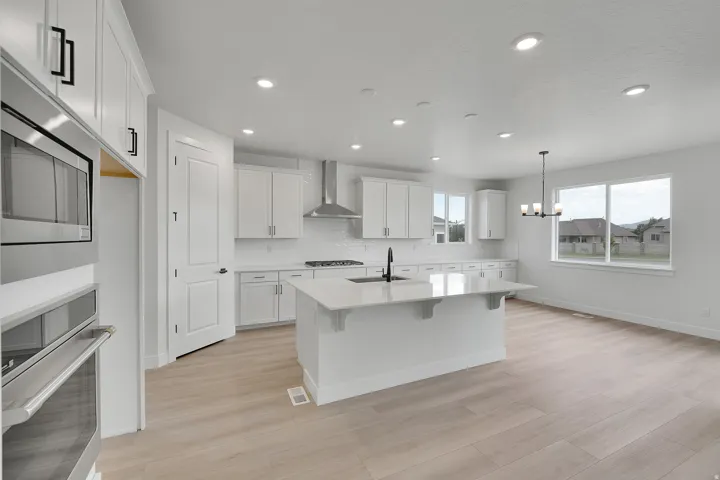 Gourmet kitchen featuring white cabinetry, a central island with countertop, stainless steel appliances, and wood-finish flooring