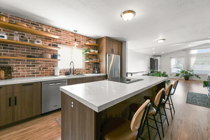 Kitchen featuring brick-style backsplash, integrated cooktop, stainless steel appliances, wood-finish flooring, and white countertops