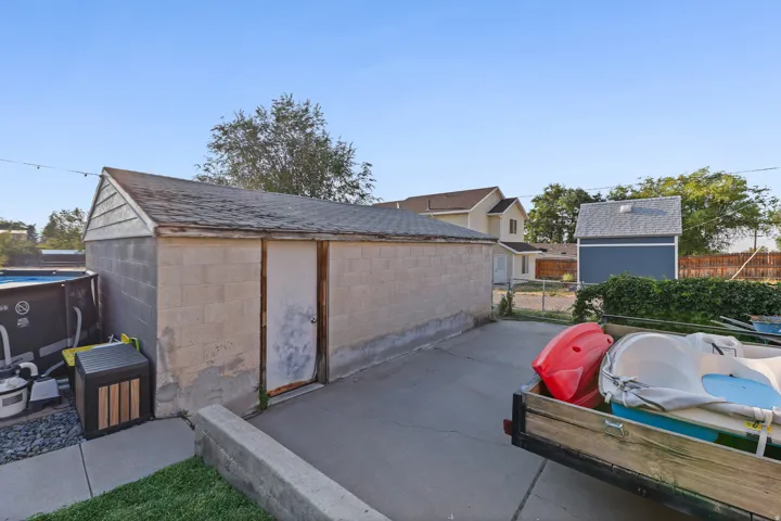 Concrete block outbuilding with a shingled roof and wood siding detail