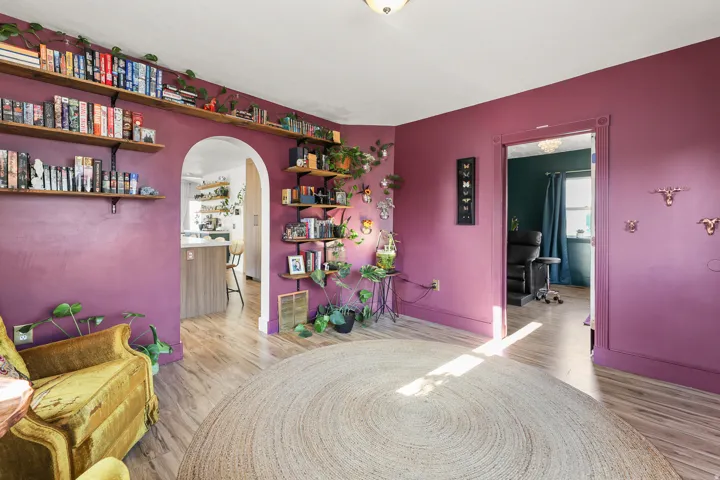Wood-finish flooring throughout, featuring a cased arched entryway and a standard cased doorway with detailed trim